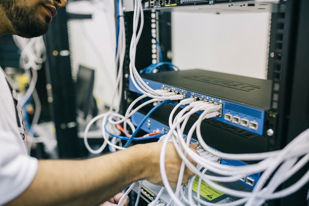 Technician connecting cables in a network equipment rack