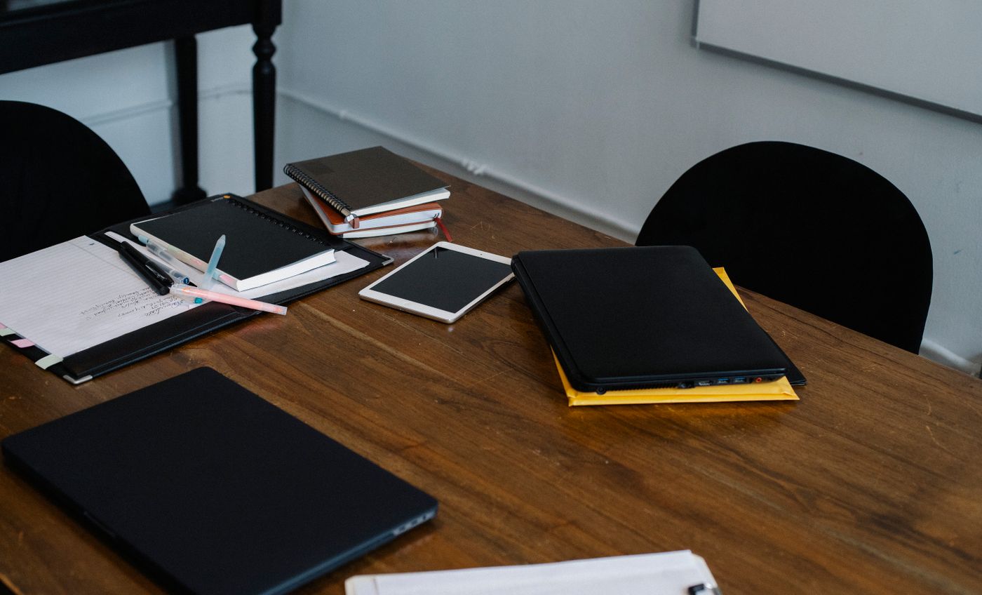 Laptop, tablet and project notebooks arranged on a shared work table