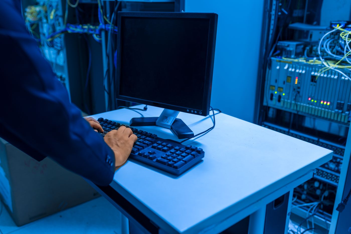 Technician operating a computer beside network equipment